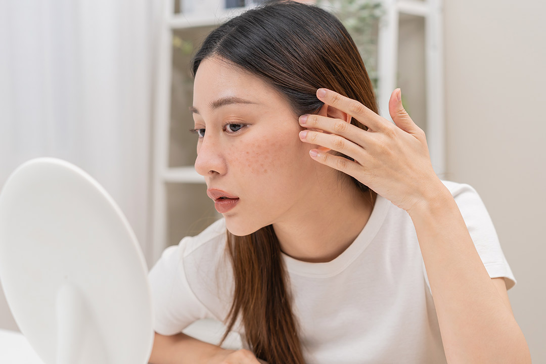 woman in front of a mirror, doing a face skin review