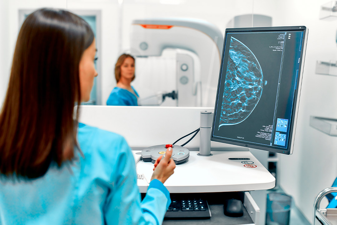In a hospital room, a woman studies a computer screen displaying cancer prevention resources.