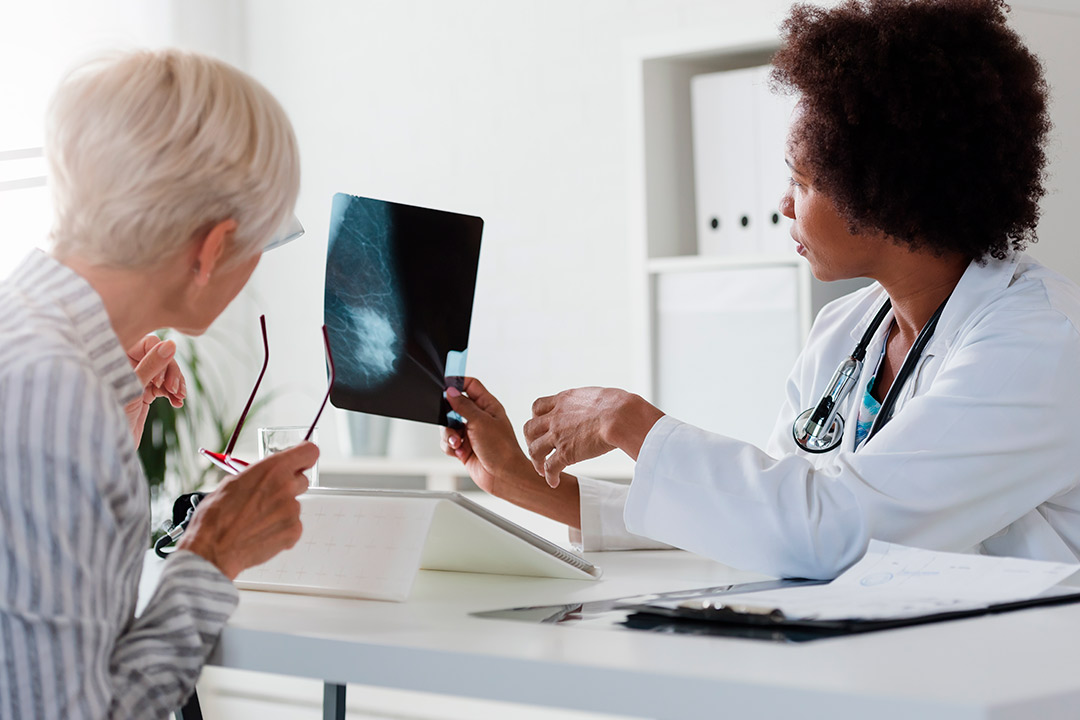 A woman studies an X-ray on a tablet, emphasizing the importance of cancer prevention.