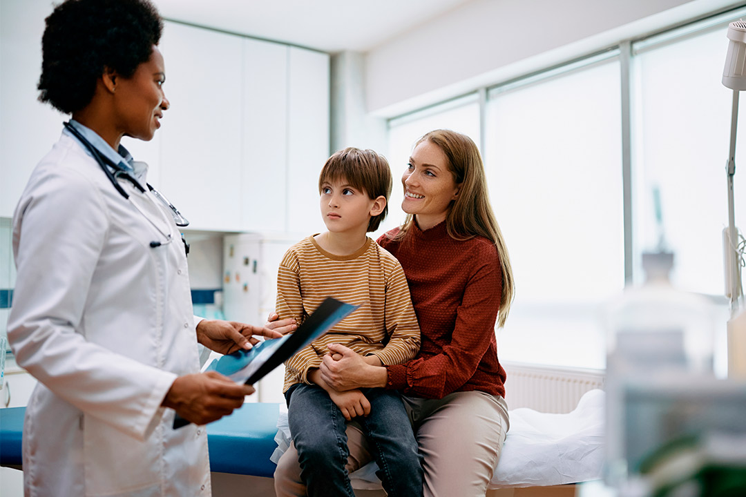 In a doctor's office, a woman and a child are seated, focusing on understanding insurance for routine medical care.